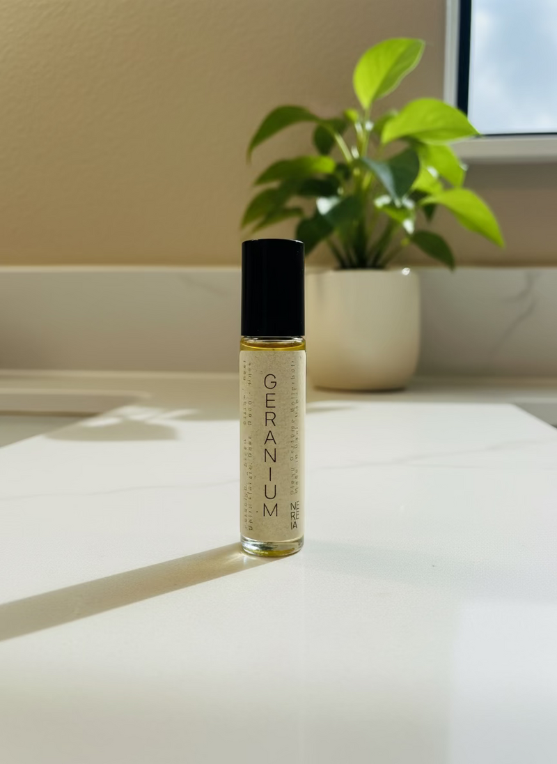 Roll-on bottle of geranium perfume oil on a wooden surface with a neutral background