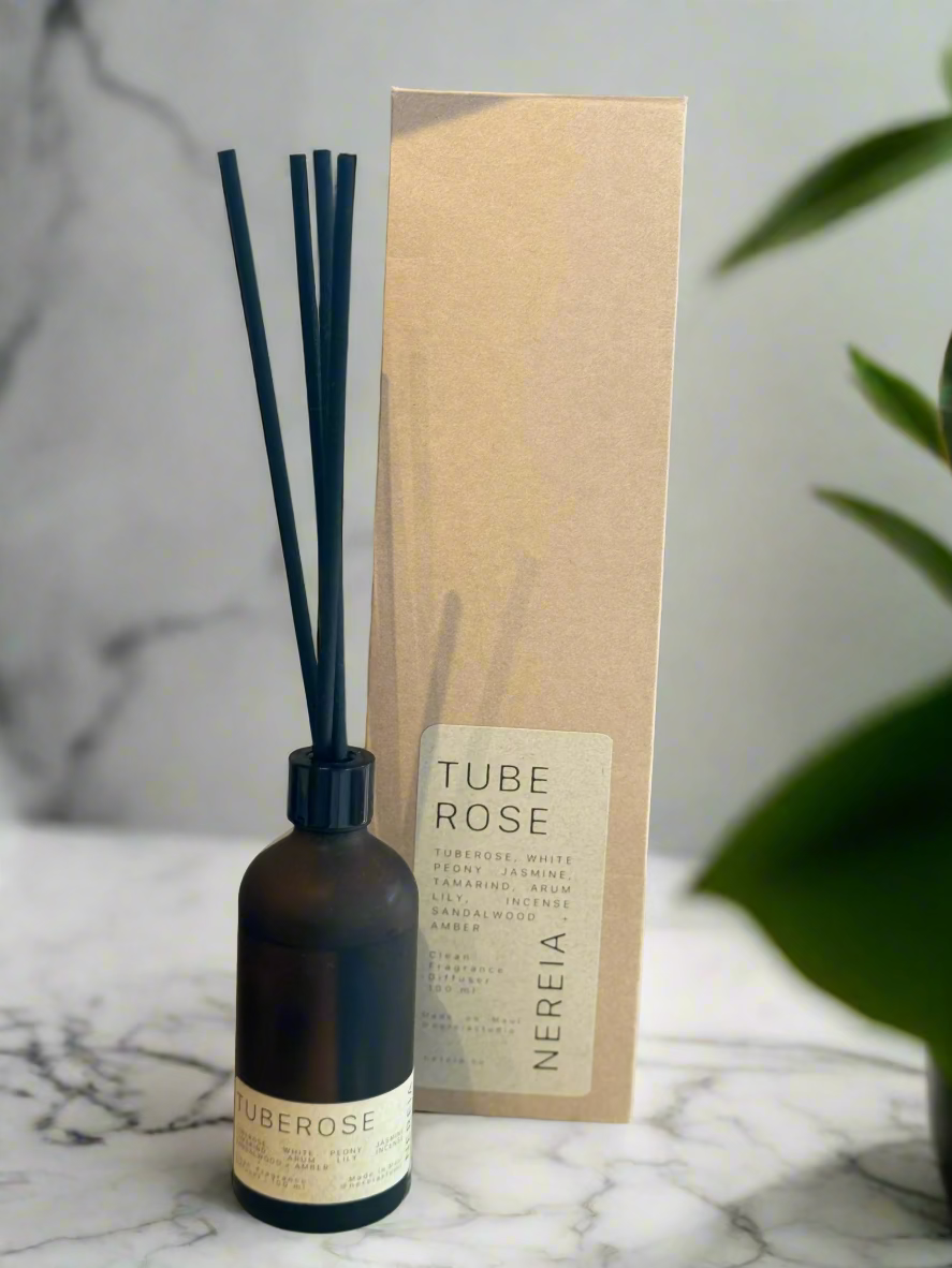 Tube Rose diffuser bottle and packaging on a marble surface with wooden background