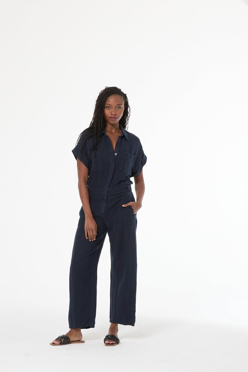 Woman wearing a navy jumpsuit on a white background