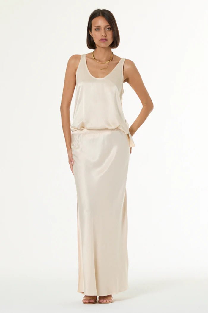 Woman wearing a long, light-colored dress against a white background