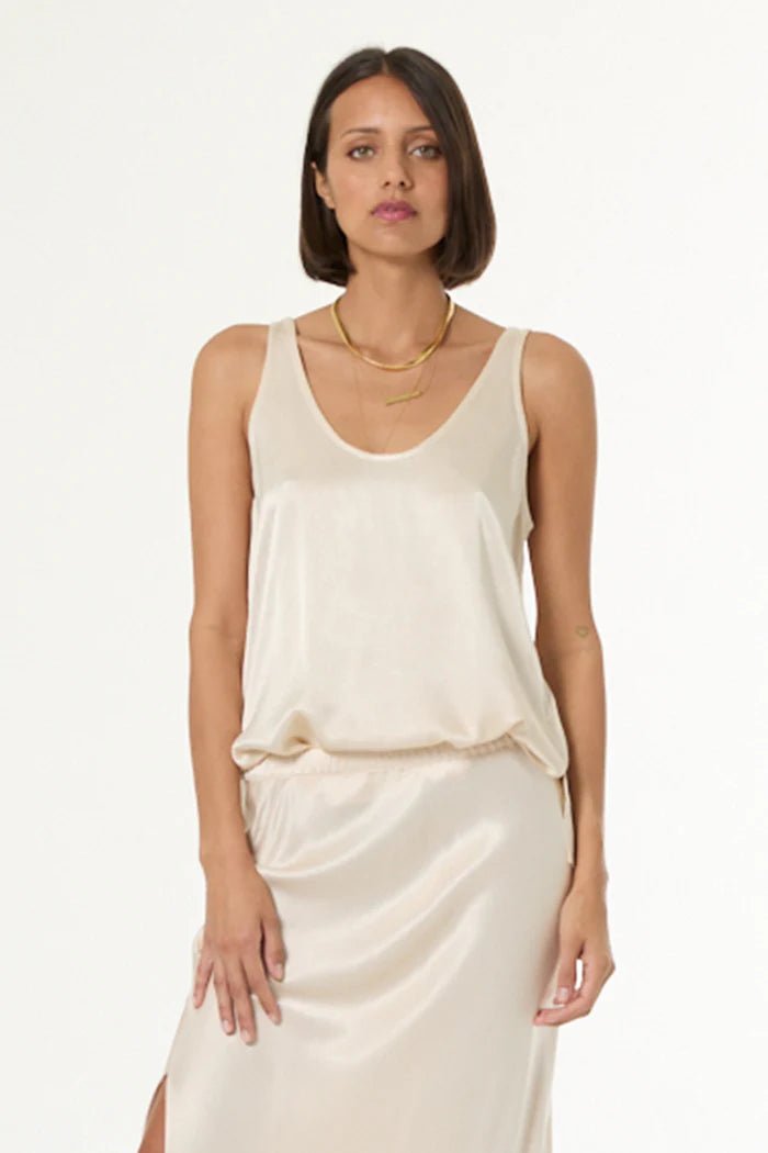 Woman wearing a beige sleeveless top and skirt set on a white background