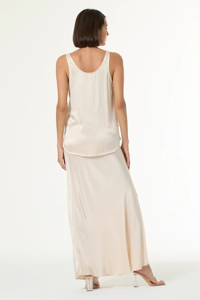 Woman wearing a beige sleeveless top and skirt set on a white background