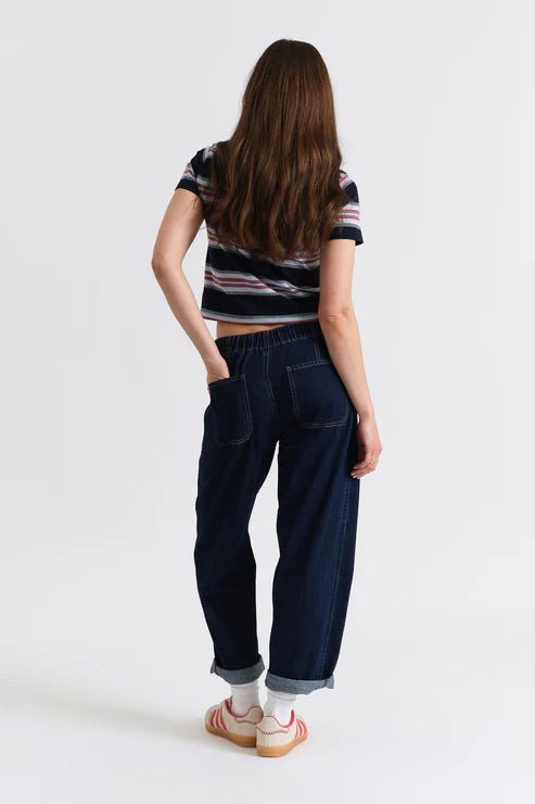 Person wearing dark blue jeans and a striped shirt on a white background